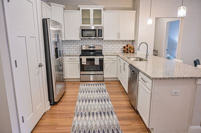 Spacious kitchen with subway tile backsplash, custom white cabinetry, stainless steel appliances and oversized breakfast bar at Hawthorne at Pine Forest in Oak Island, NC