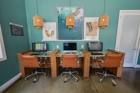 a desk with three computers and three chairs