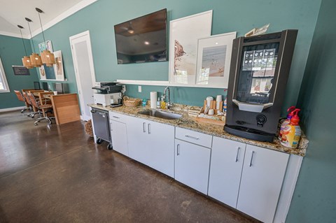 a kitchen with white cabinets and a coffee machine and a tv
