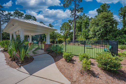 a park with a pavilion and a fence with plants and trees