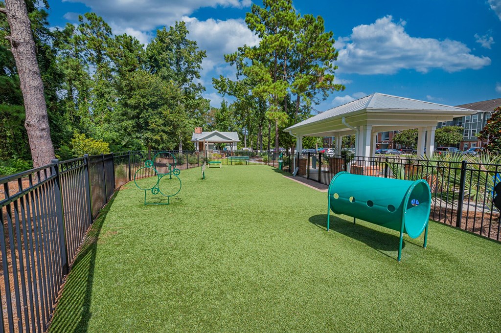 a fenced in dog park with a playground and a bench