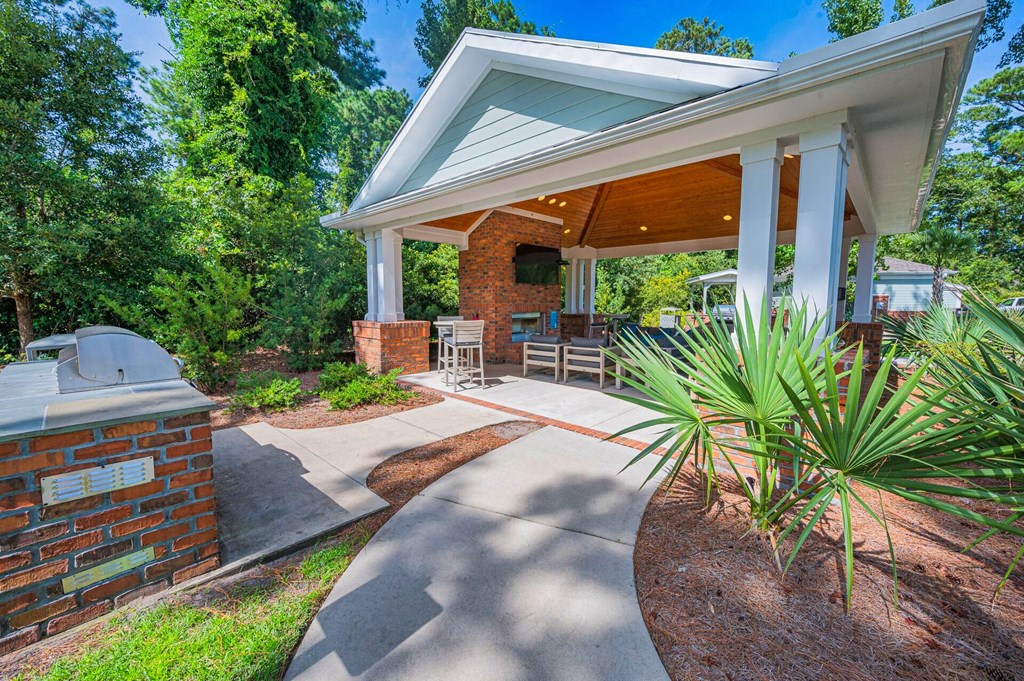 a covered patio with a grill and a house