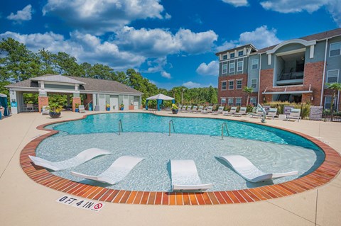 a large pool with lounge chairs in front of a building