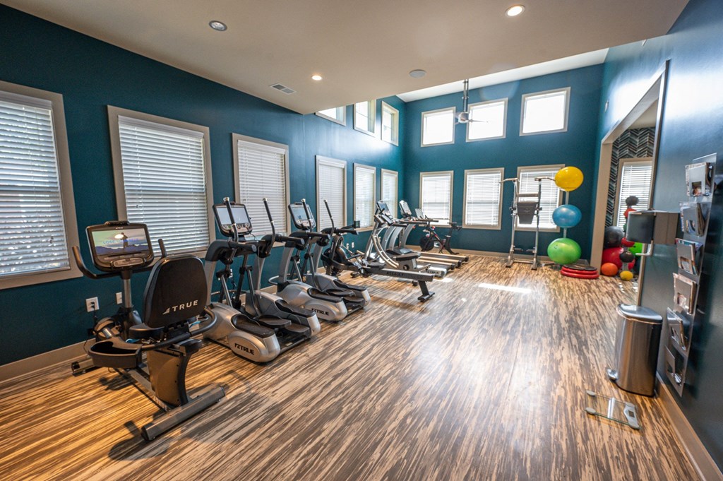 a gym with cardio machines and weights on a wooden floor