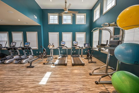 a gym with cardio equipment and weights on a wood floor