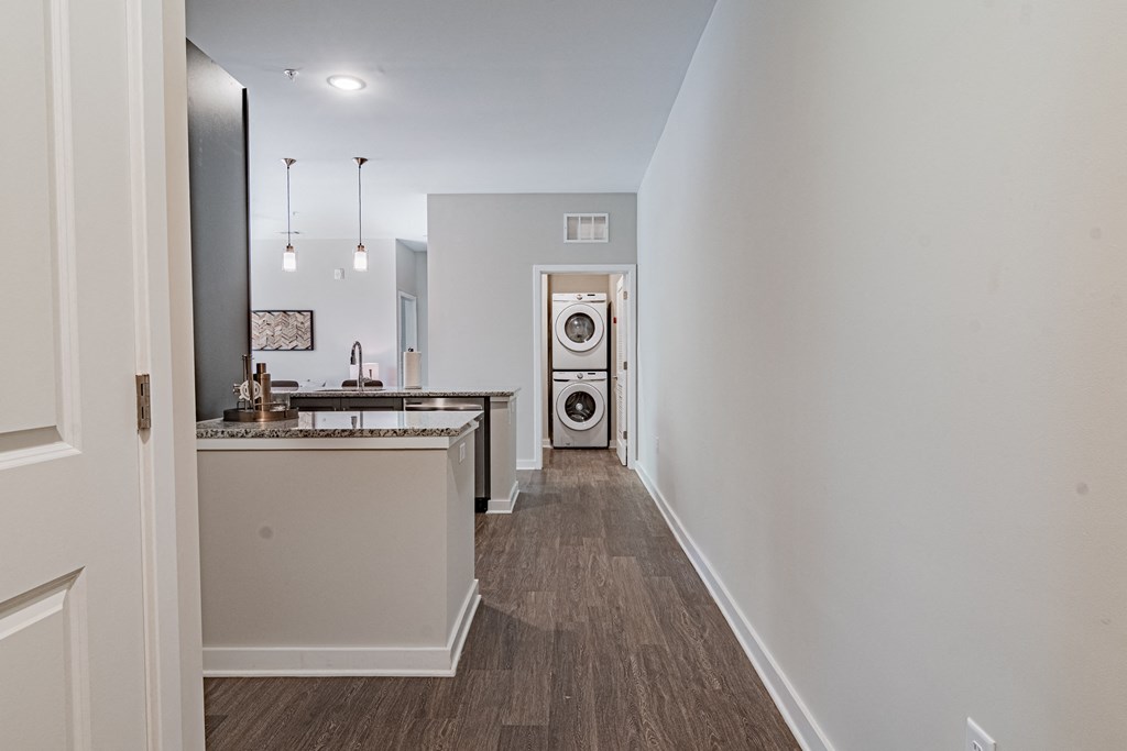 a long hallway with a kitchen and a washing machine in the distance