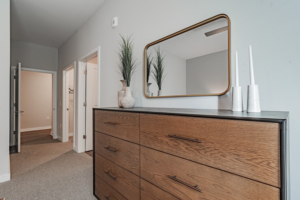 a bedroom with a dresser with a mirror and a hallway with a door