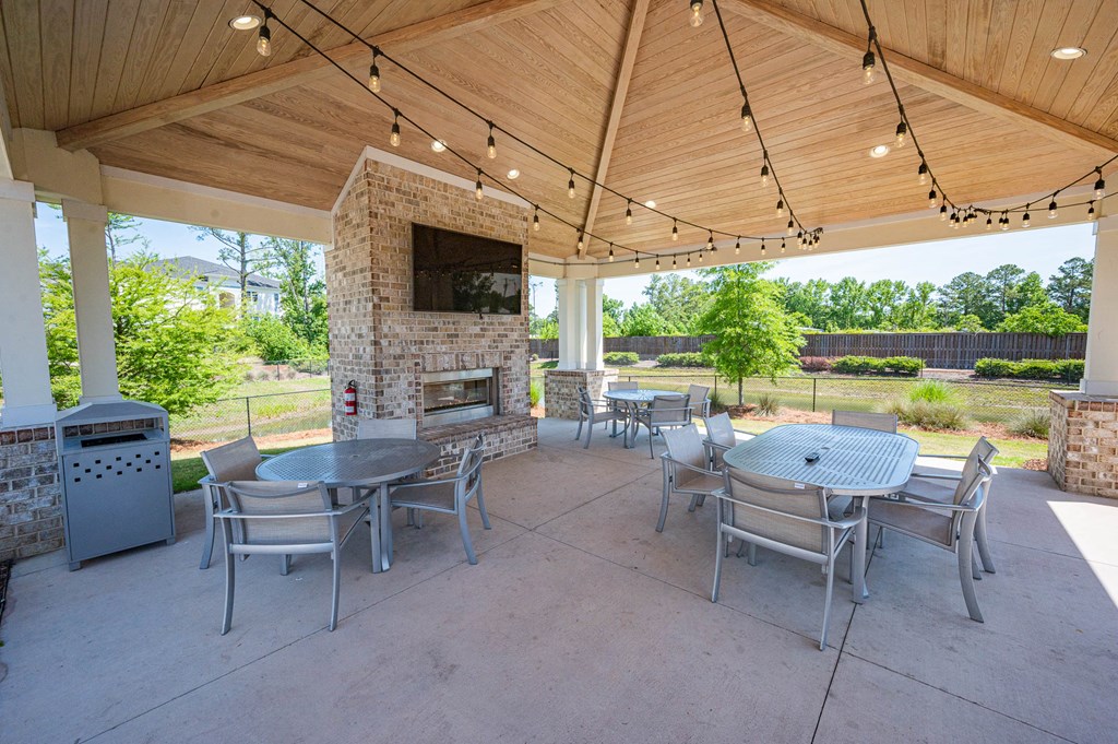 a covered patio with tables and chairs and a fireplace