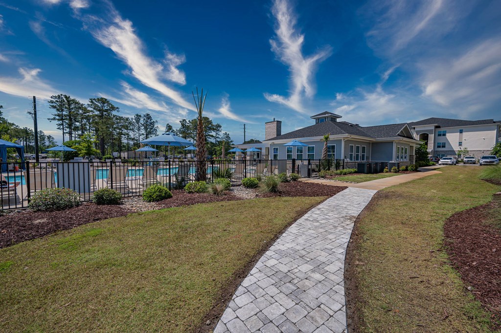 a walkway leading to a house with a pool