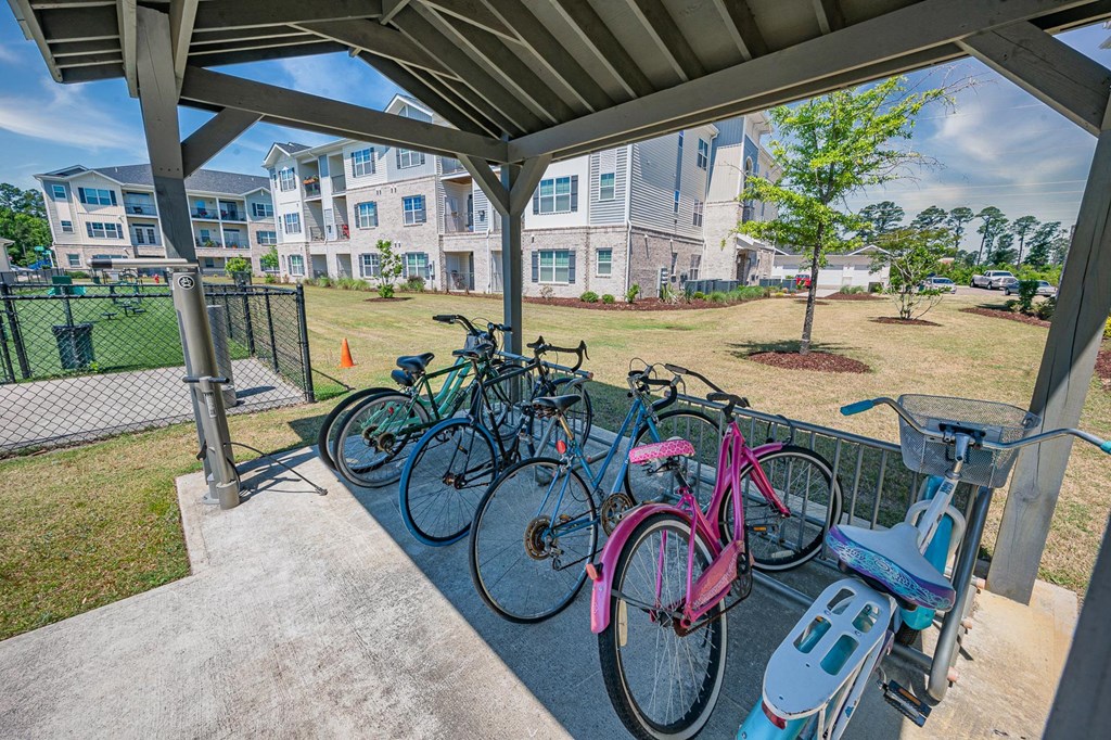 a row of bikes parked at a bike rack with apartments in the background