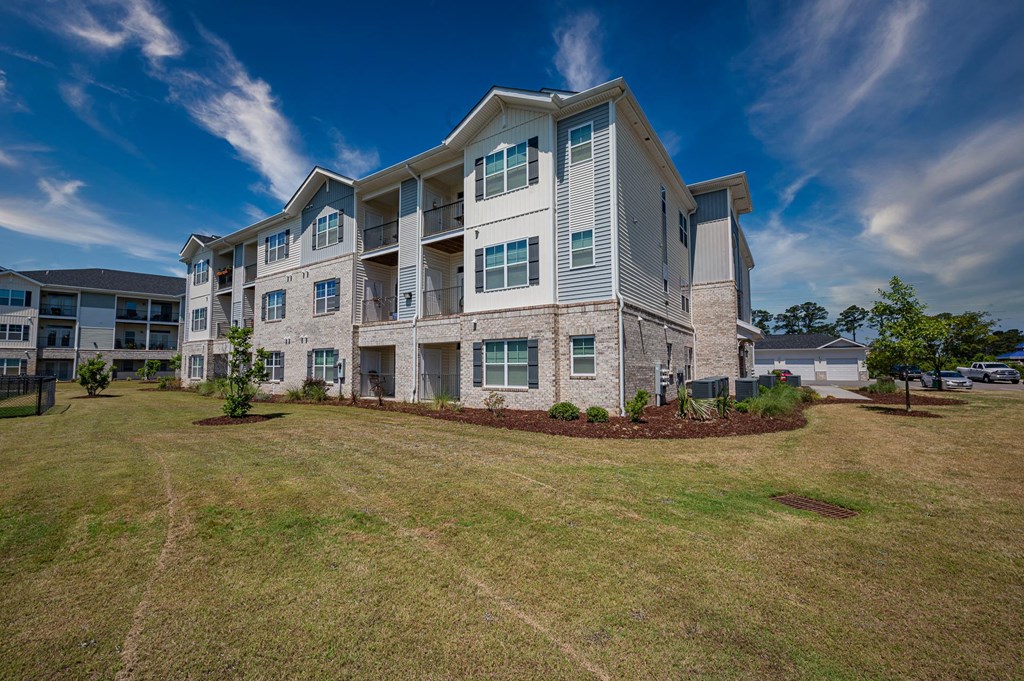 a large apartment building with green grass and a blue sky