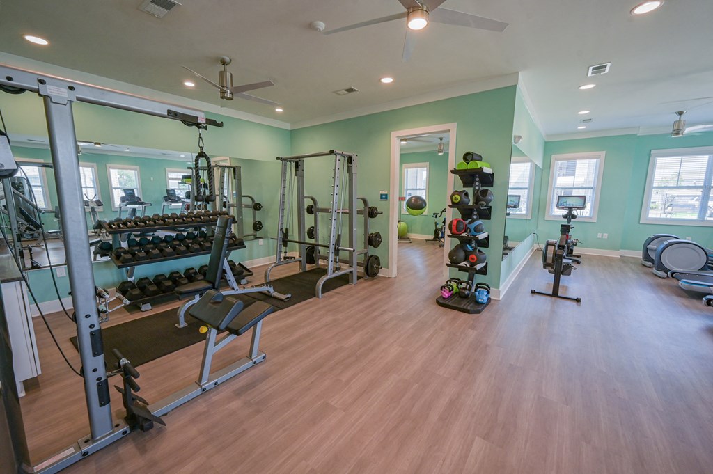 a gym with a lot of weights and equipment on a wooden floor