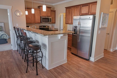 a kitchen with an island with bar stools and a stainless steel refrigerator