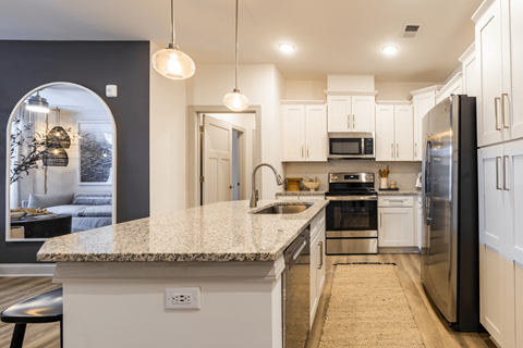 a kitchen with white cabinets and a marble counter top