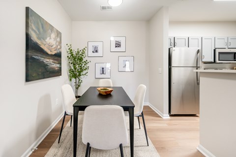 A dining room with a black table and white chairs.