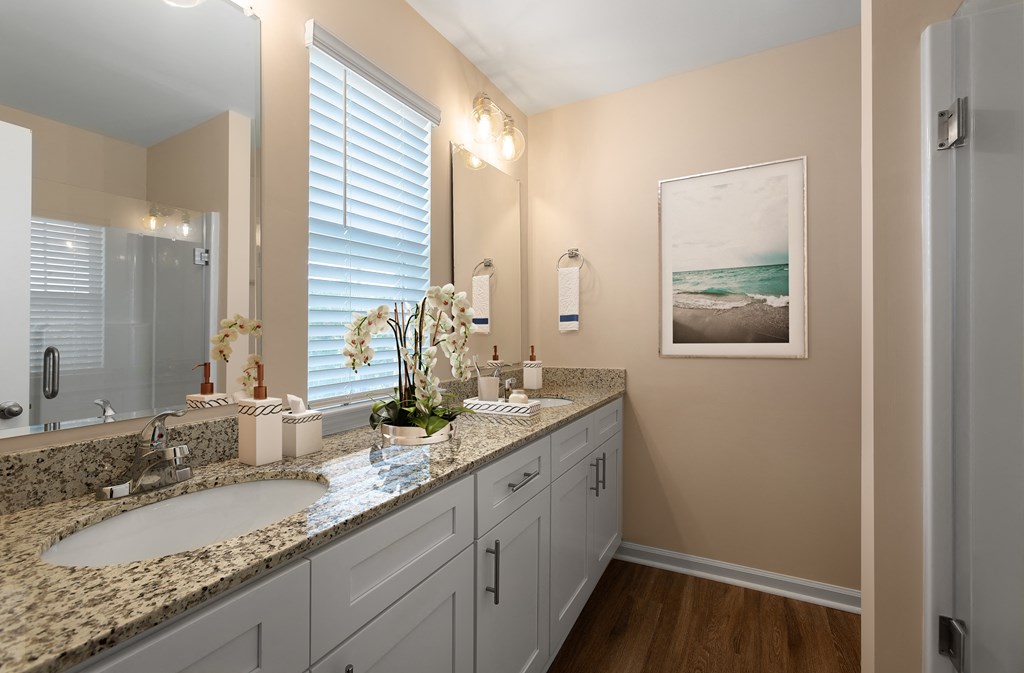 A bathroom with a large mirror, a sink, and a framed picture on the wall.