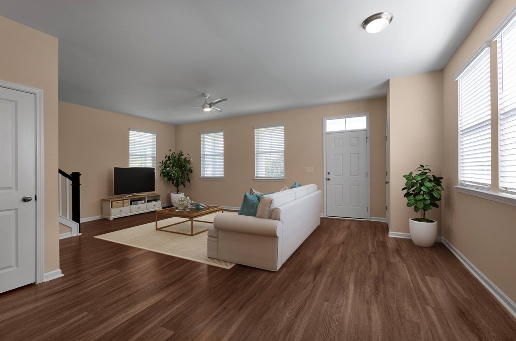 A living room with a white couch, a television, and a potted plant.