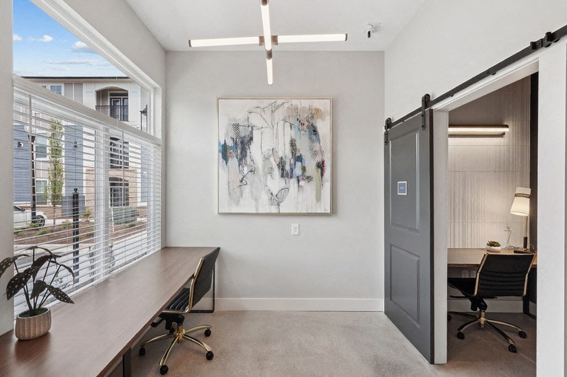 an office with a desk and a door to a room with a window