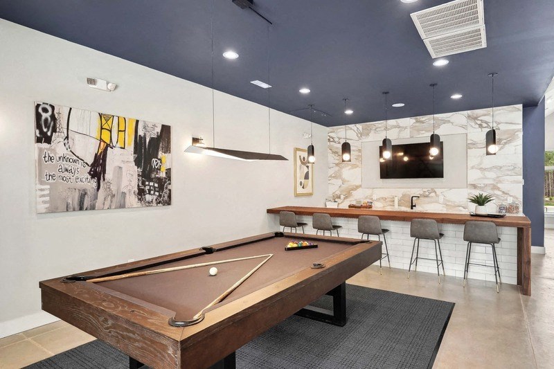 a pool table in a clubhouse with a bar and a television