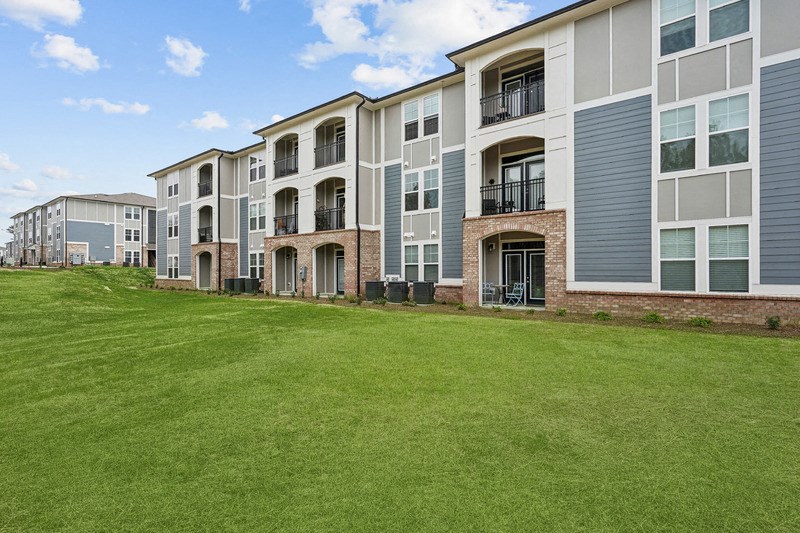 an exterior view of an apartment building with green grass