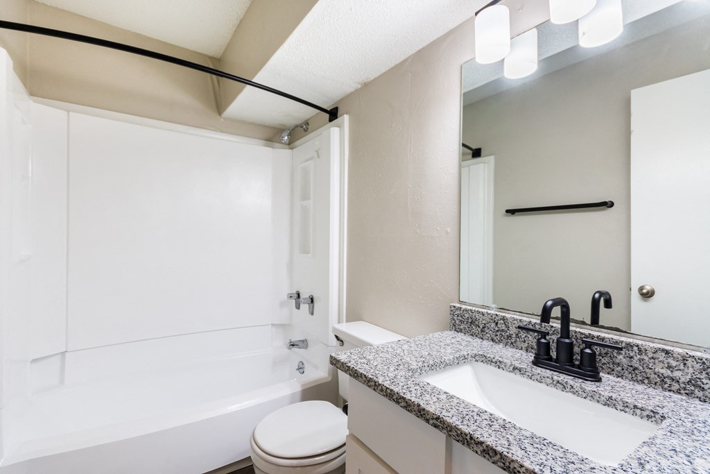 A bathroom with a toilet, sink, and mirror.