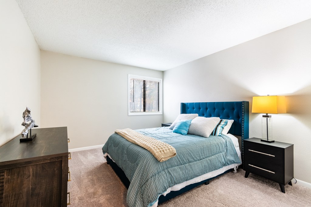 A bedroom with a bed, nightstand, and a lamp.