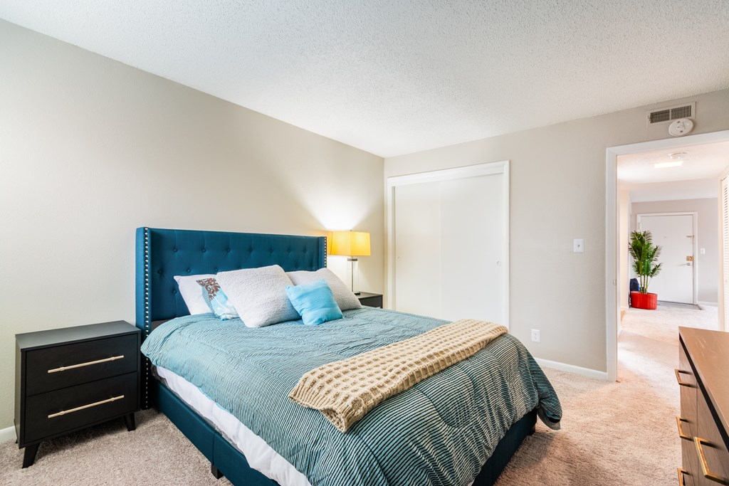 A bedroom with a blue headboard and a bed with a green comforter.
