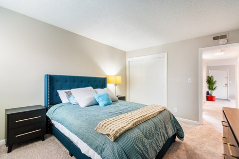 A bedroom with a blue headboard and a bed with a green comforter.