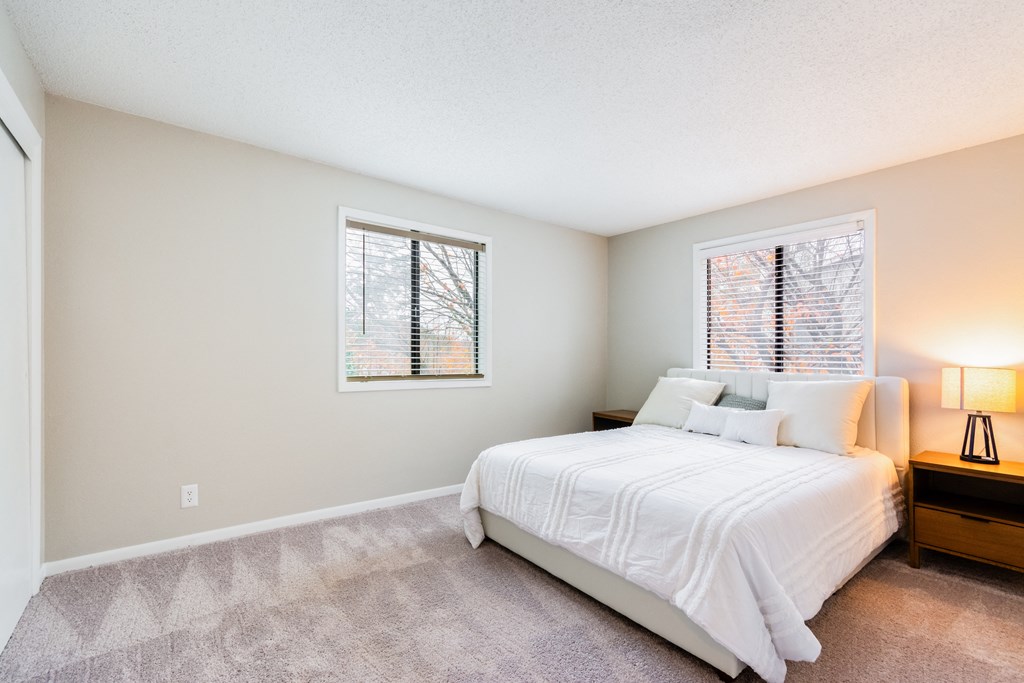 A bedroom with a bed, nightstand, and window.