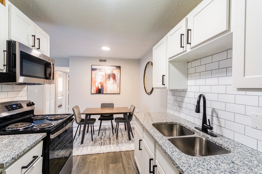 A kitchen with a black stove top oven and a black microwave above it.