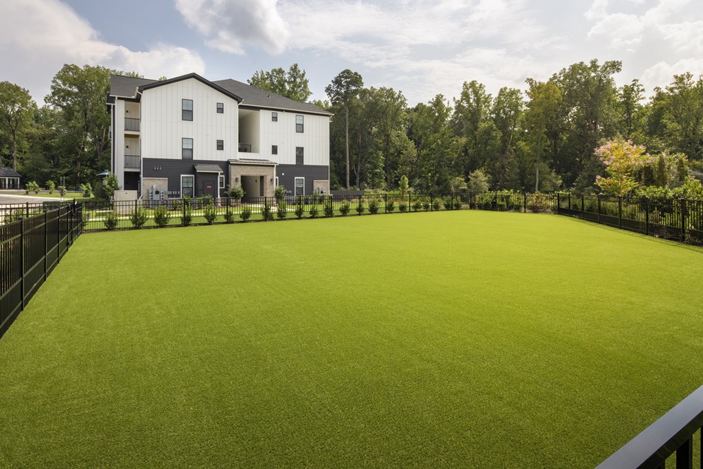 A large grassy area in front of a two-story building.