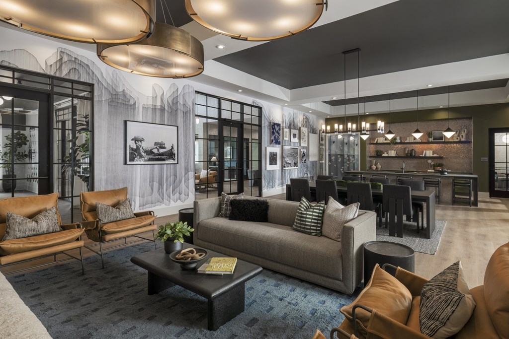 A modern living room with a grey sofa, a coffee table, and a large window with a view of a tree.