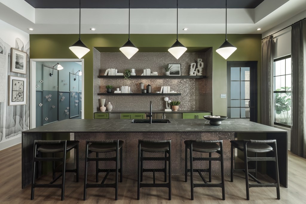 A modern kitchen with a dark countertop and bar stools.