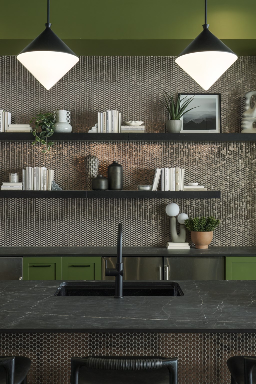 A kitchen with a black countertop and green cabinets.