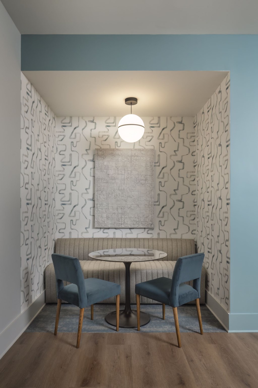 Two chairs and a table are in a room with a patterned wallpaper.