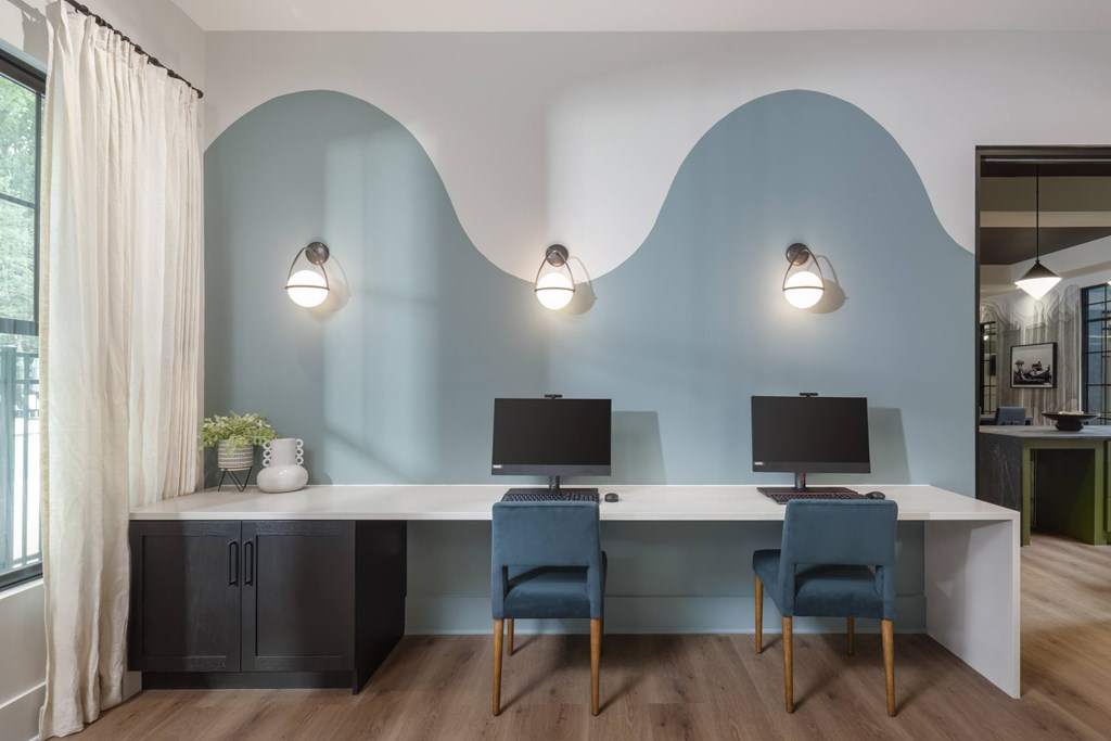 A room with a desk, two chairs, and two wall-mounted lights.