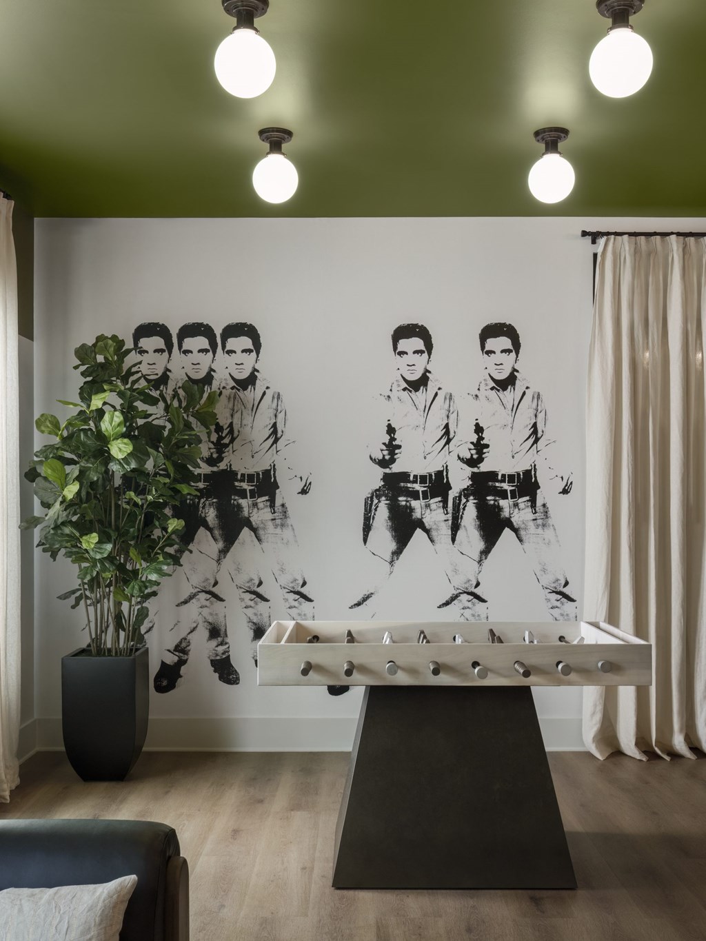 A black and white photo of a man is on the wall above a pool table.