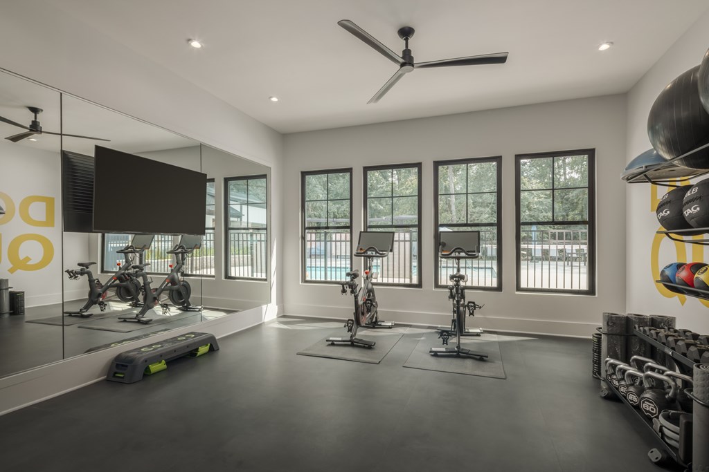 A spacious gym with a variety of exercise equipment and large windows.