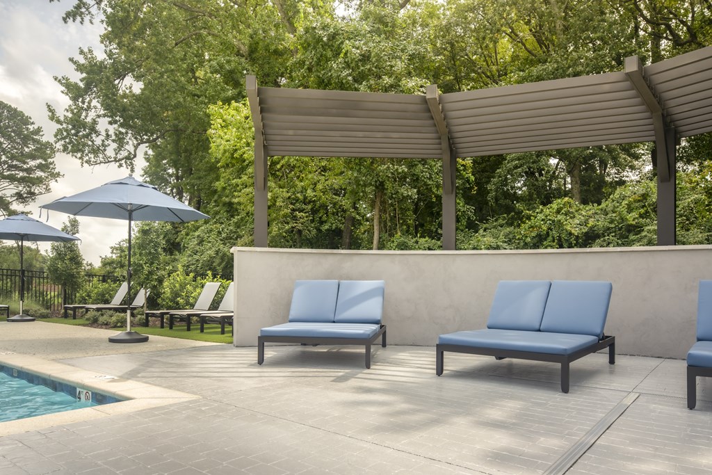 A poolside area with a bench, umbrella, and a pool.