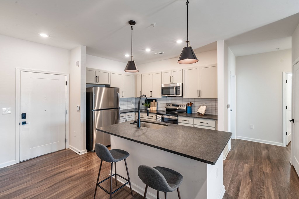 a kitchen with a large island and a stainless steel refrigerator