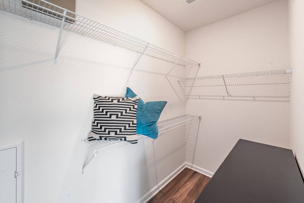 a spacious closet with a table and a chair in a room with white walls