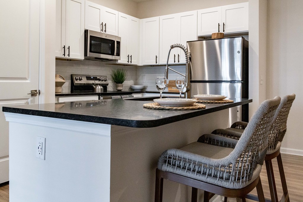 A kitchen with a black countertop and white cabinets. at Evolve Waterford Apartments in Belville, NC