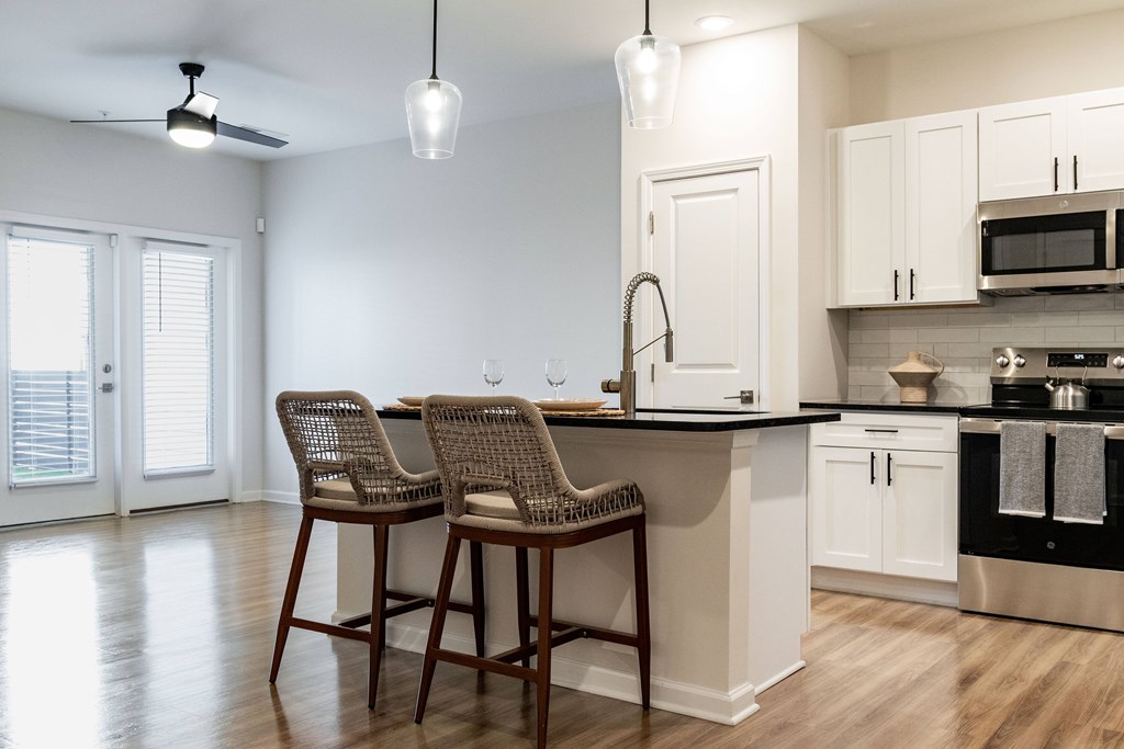 A kitchen with bar stools and a counter at Evolve Waterford Apartments in Belville, NC