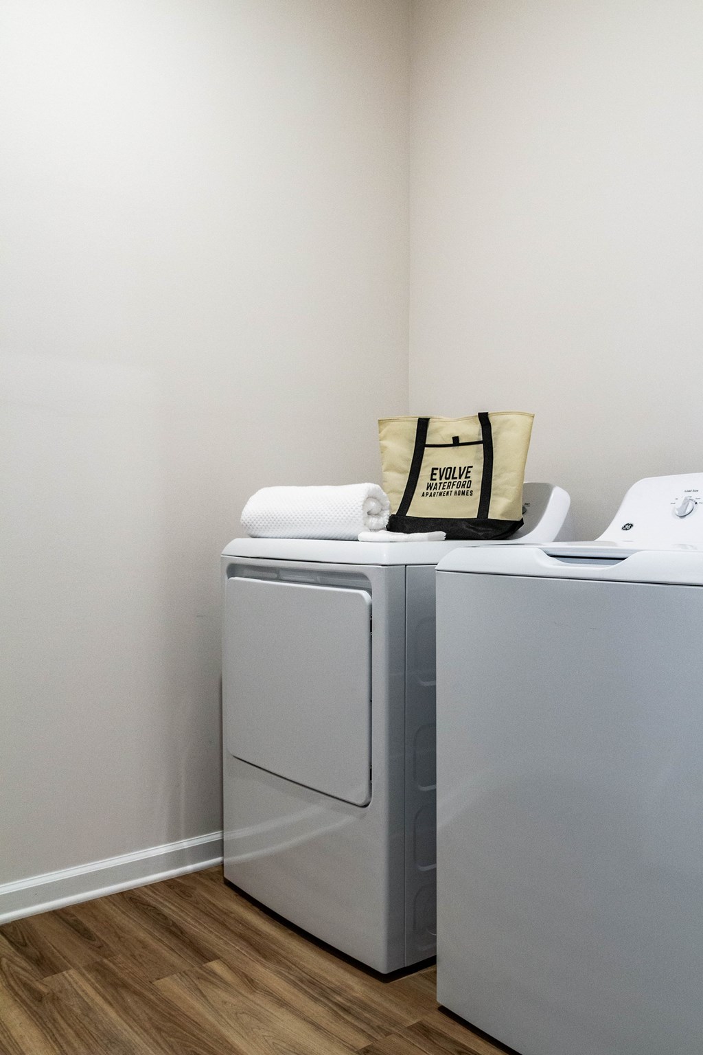 A white washing machine with a bag on top of it. at Evolve Waterford Apartments in Belville, NC