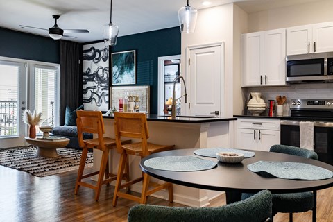 A kitchen with a table and chairs in front of it.