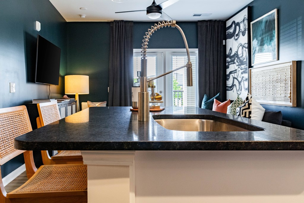 A modern kitchen with a black countertop and a sink. at Evolve Waterford Apartments in Belville, NC