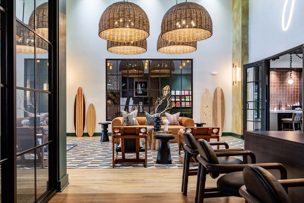 A modern clubhouse with wooden chairs and tables at Evolve Waterford Apartments in Belville, NC
