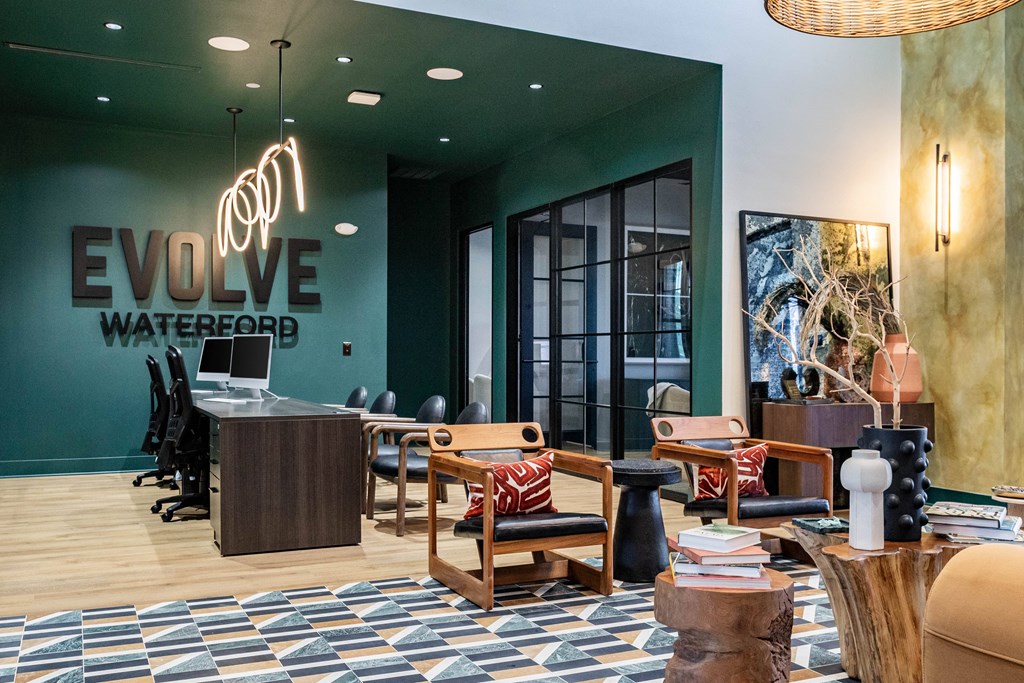 A modern clubhouse with a green wall and seating area at Evolve Waterford Apartments in Belville, NC