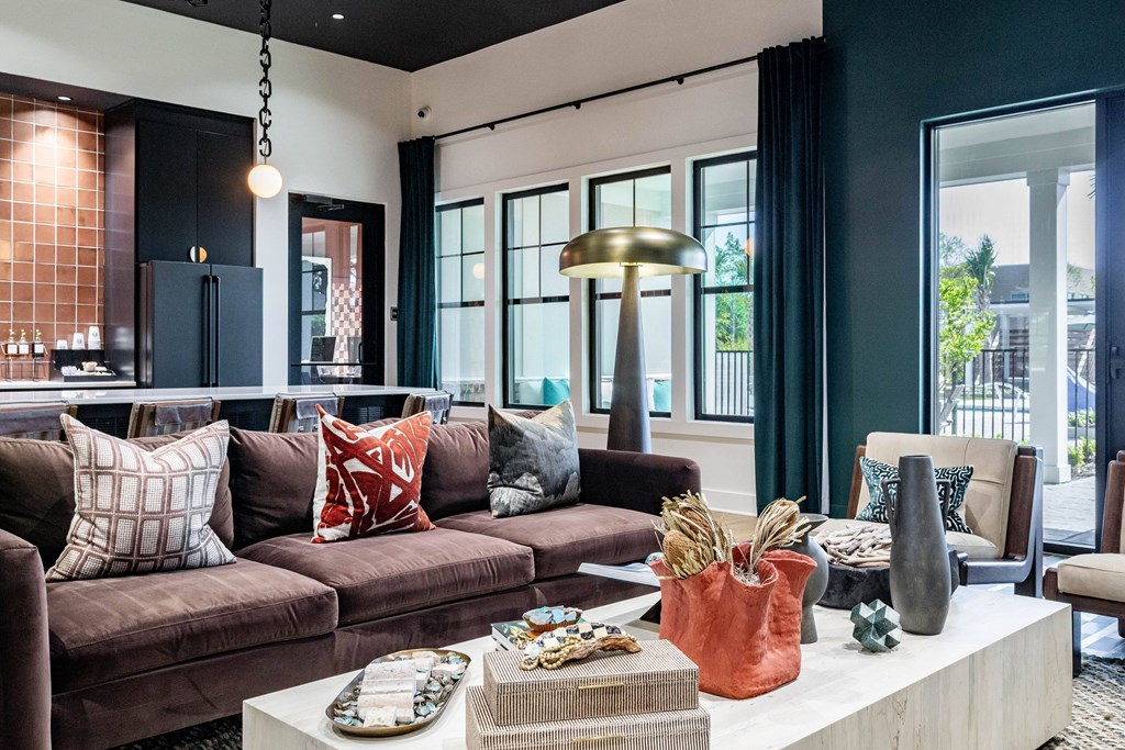 A clubhouse with a brown couch and a coffee table with various objects on it at Evolve Waterford Apartments in Belville, NC