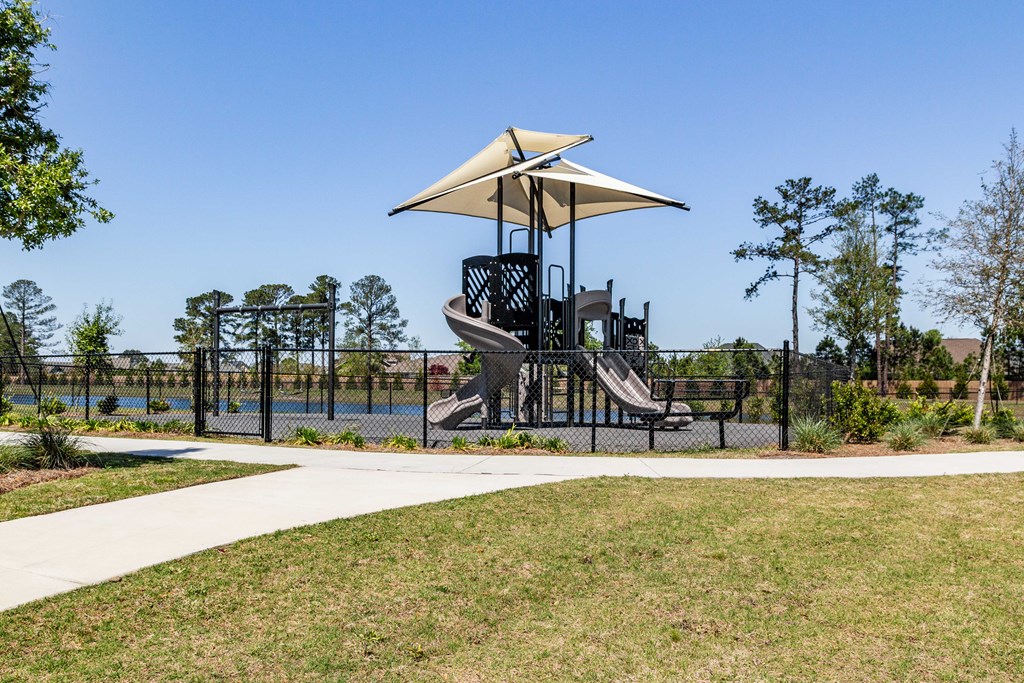 A playground with a slide and a canopy. at Evolve Waterford Apartments in Belville, NC